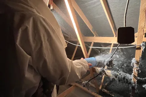 Applicateur Isolatech en plein soufflage de laine de coton dans les combles, charpente bois apparente · Saint-Barthélemy (70200, près de Lure, Haute-Saône) · Isolatech