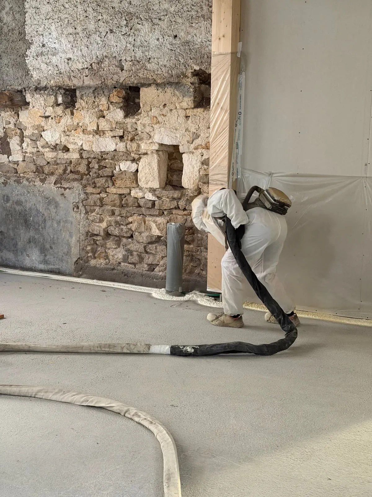 Applicateur Isolatech projetant la mousse polyuréthane sur mur en pierre brute