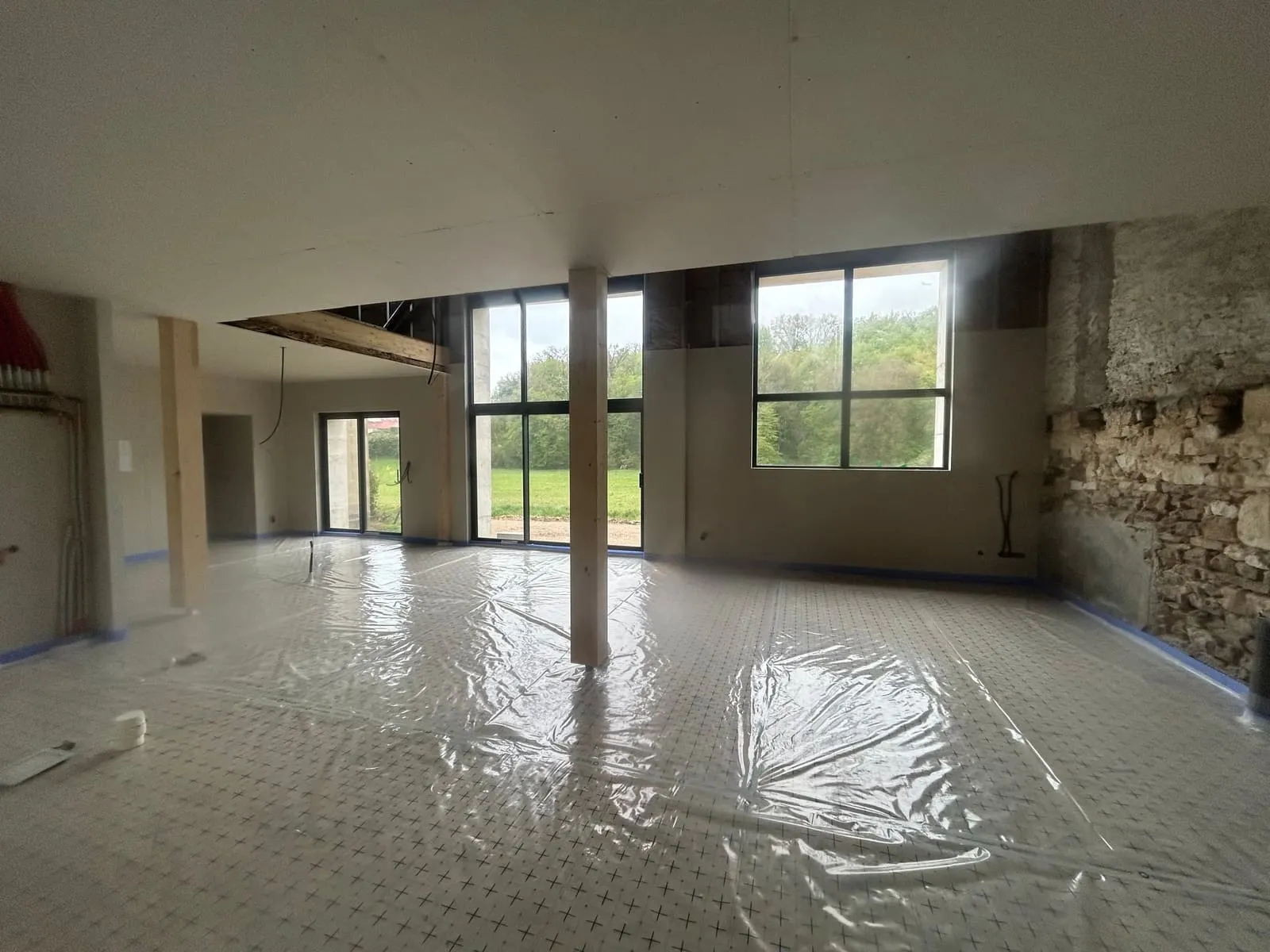 Salon avec mur en pierre apparente et baies vitrées après isolation des sols polyuréthane à Pérouse